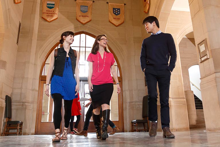 Three people converse as they walk through the halls of the Indiana Memorial Union.